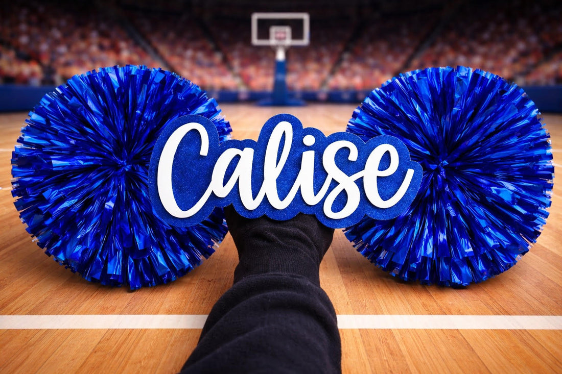 Blue pom-poms with 'Calise' text held by a person on a basketball court
